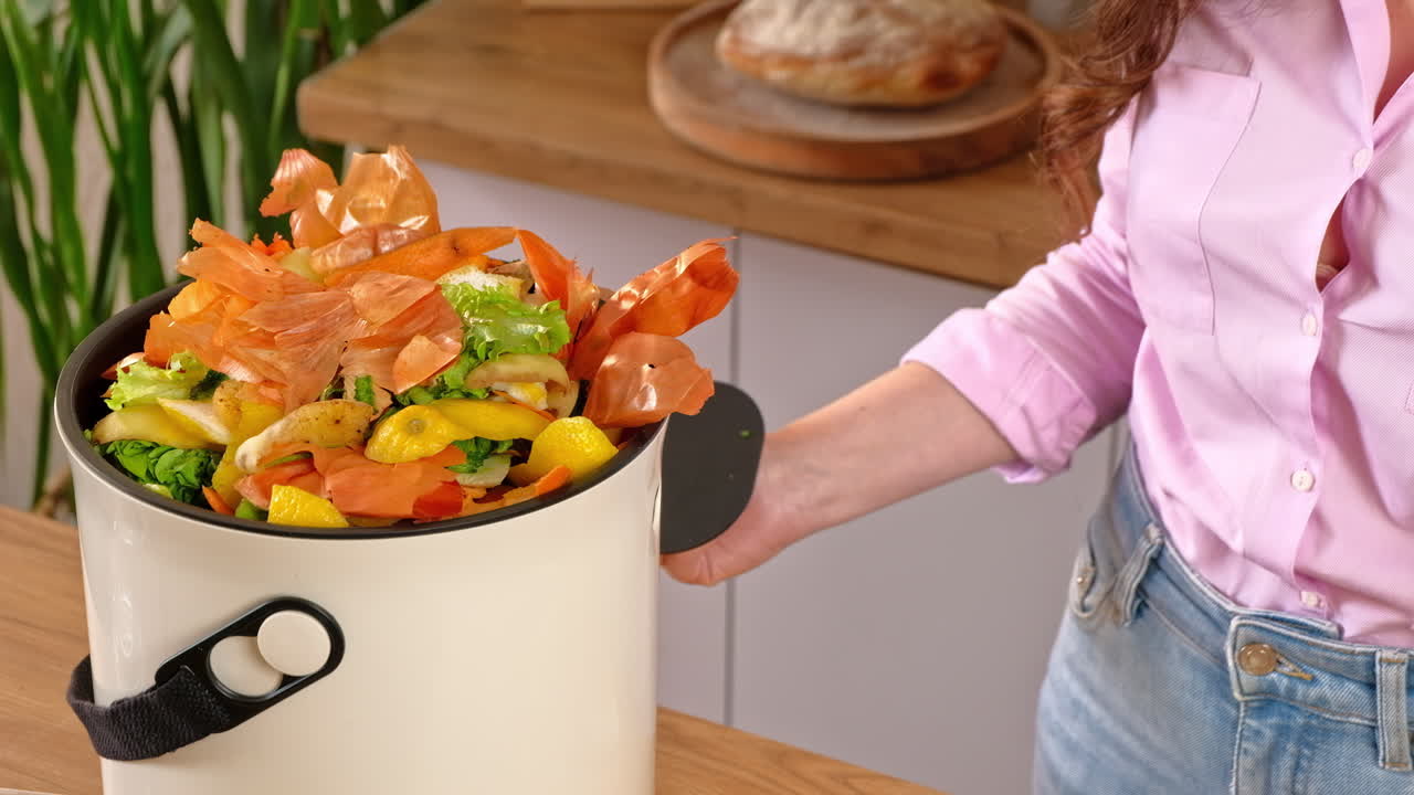 Woman recycling organic waste by composting vegetables peels in the Bokashi in the kitchen
