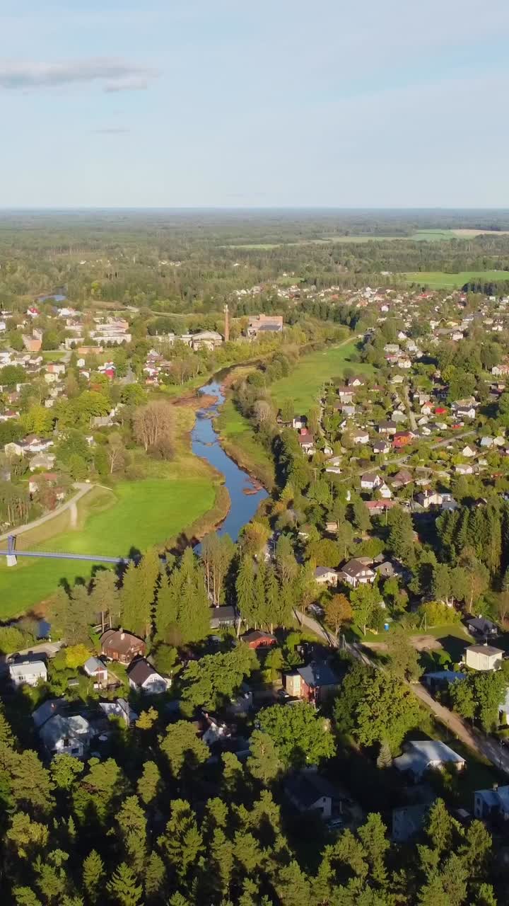 Ripresa con drone soleggiata di un'area urbana verde con un fiume, carrellata all'indietro con alcune nuvole, spazio per il testo