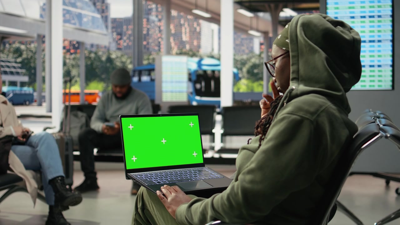 Notebook mockup con schermo verde usato da un viaggiatore nel terminal degli autobus