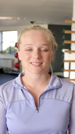 vertical video: smiling woman in rehabilitation center, wearing athletic wear, arms crossed