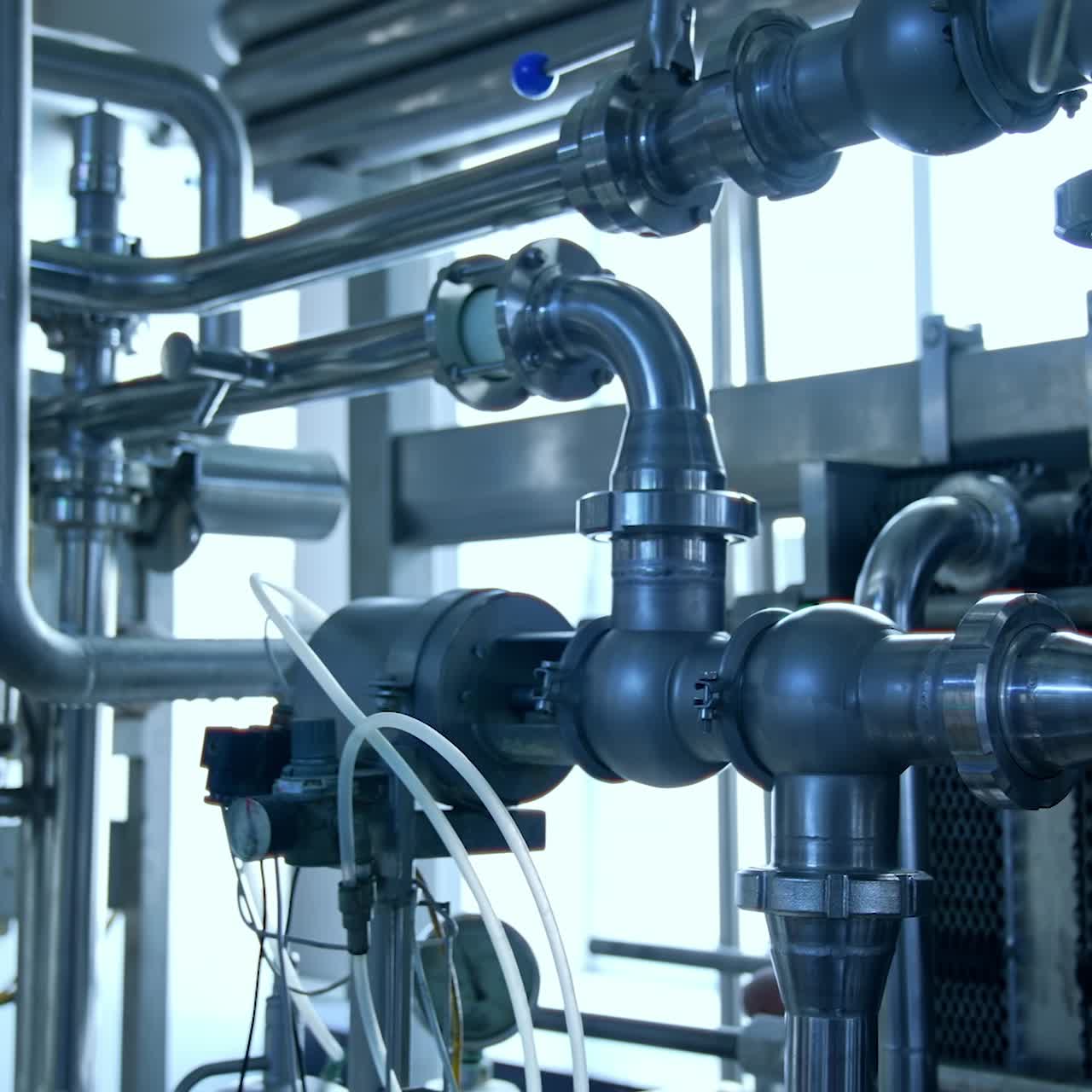 Dairy food production plant. Slow motion along the system of pipelines at diary food industry enterprise. Close up