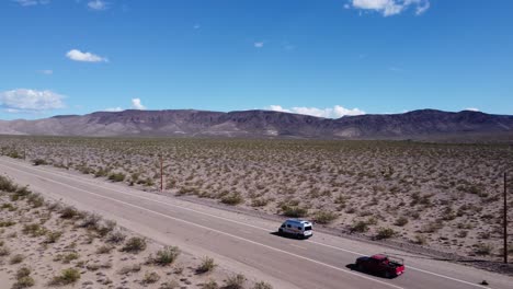 drone shot of an rv parked on dirt road by mountain range
