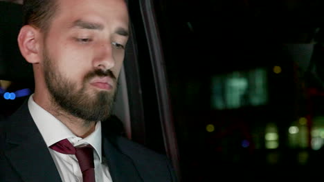 hombre de negocios barbudo trabajando en una computadora portátil desde el asiento trasero de su limusina