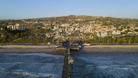 sobrevuelo aéreo del muelle de san clemente con embarcadero, playa de arena y hermoso paisaje urbano en la colina