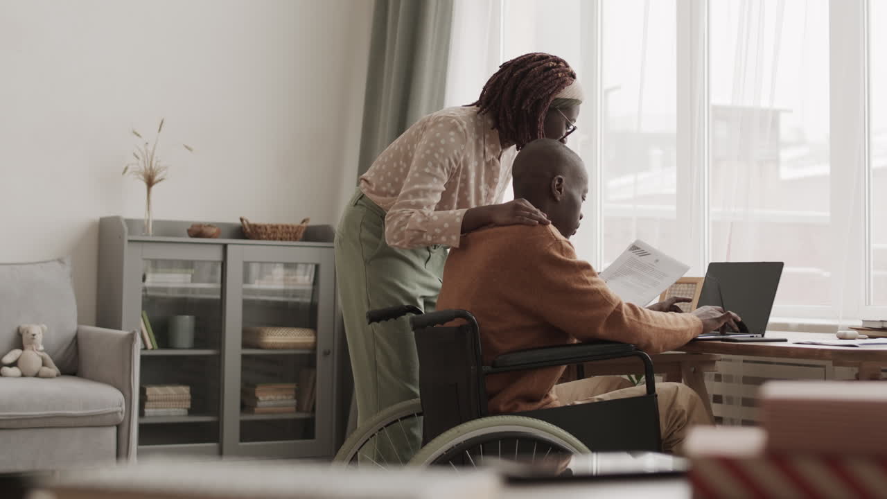 Woman Helping Handicapped African-American Man Doing Paperwork
