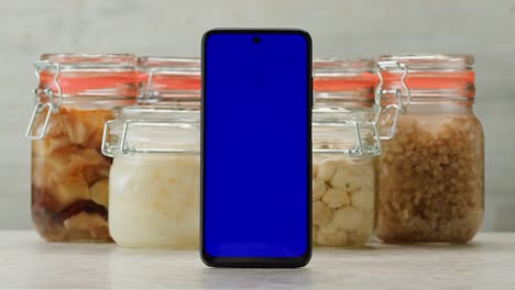 smartphone in front of jars of preserved food