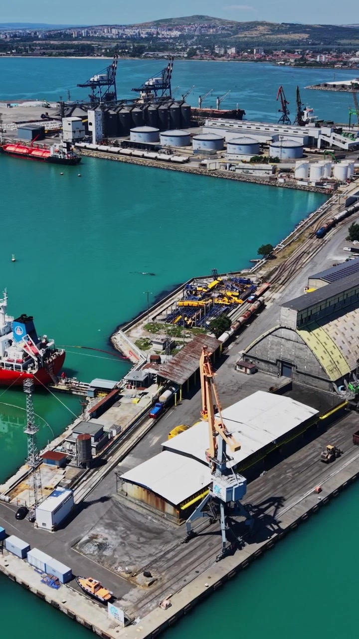 Una grande nave rossa è attraccata al molo di un porto trafficato.