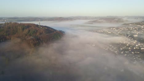 misty sunrise in morsbach, north rhine-westphalia with thick fog floating through the valleys of the brown hills