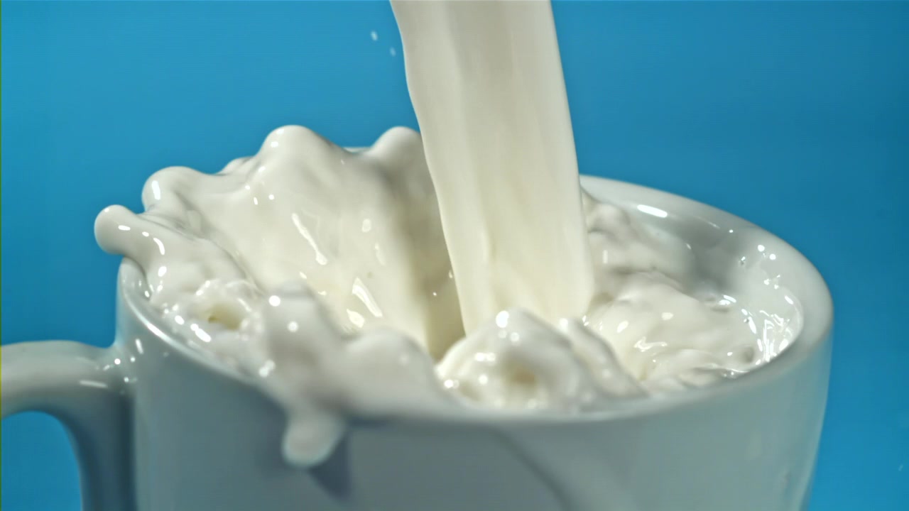 白いマグカップに牛乳が注がれ、溢れ出すスローモーション。