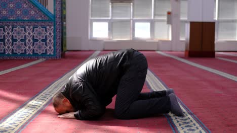 muslim man kneels during prayer in mosque