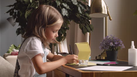 blonde girl sitting at the desk while working with cardboard 1