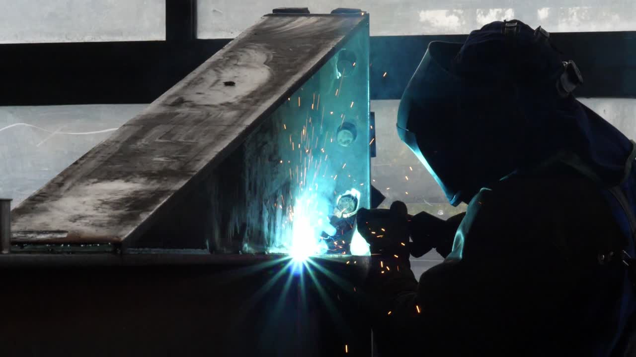 Crafting brilliance: Dive into the sparks and skill as a welder shapes metal in this mesmerizing stock footage snippet