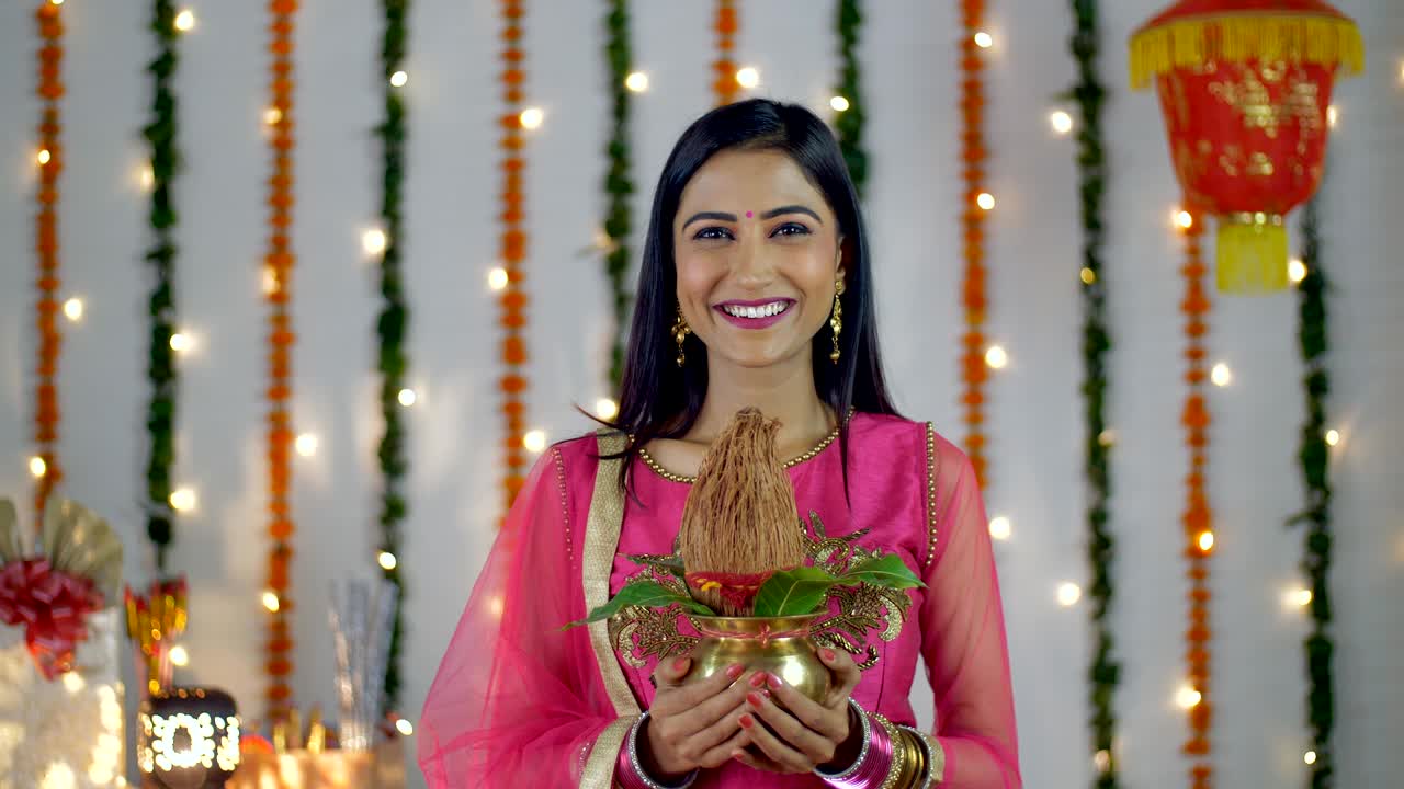 A young woman smiling while holding a Puja Kalash in her hands - Diwali festival