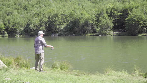 Man-fishing-in-a-mountain-lake,-4K