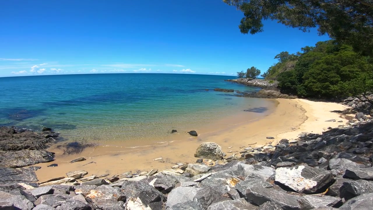 Secret beach with blue water and blue sky, no clouds. Rocky descent serene beach