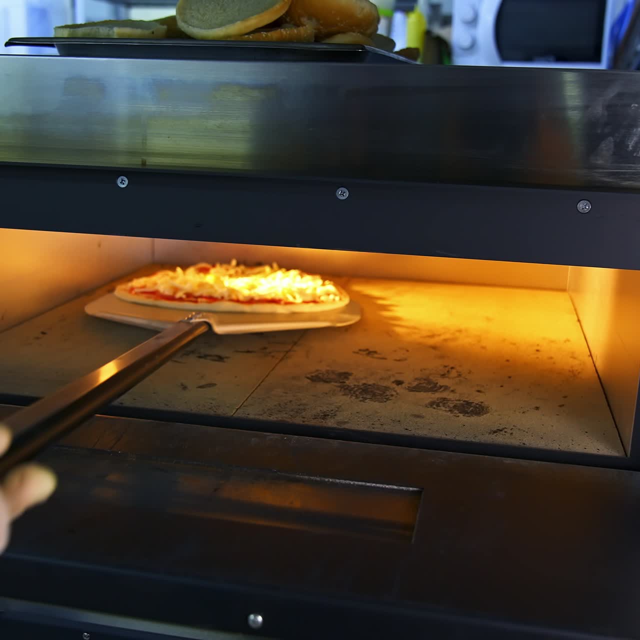 Freshly Prepared Pizza on a Wooden Table in a Cafe. Appetizing hot pizza close-up on the background of the interior of a modern restaurant