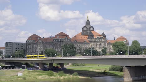 clouds drift over large building on bridge reflecting in river