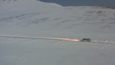 a convoy of cars going towards the most northern part of europe, the nordkapp, during a cold and dark winter day