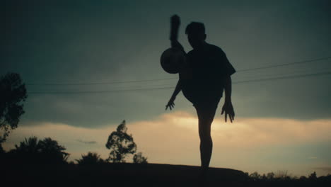 dribbling the football, slow motion, silhouette of player in dramatic lighting