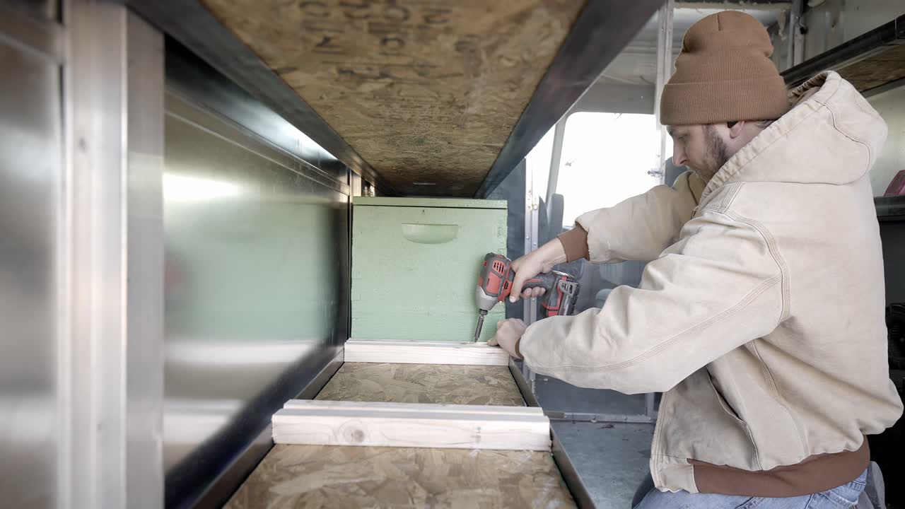 подрядчик использует аккумуляторную дрель для сверления или прикручивания деревянных полок