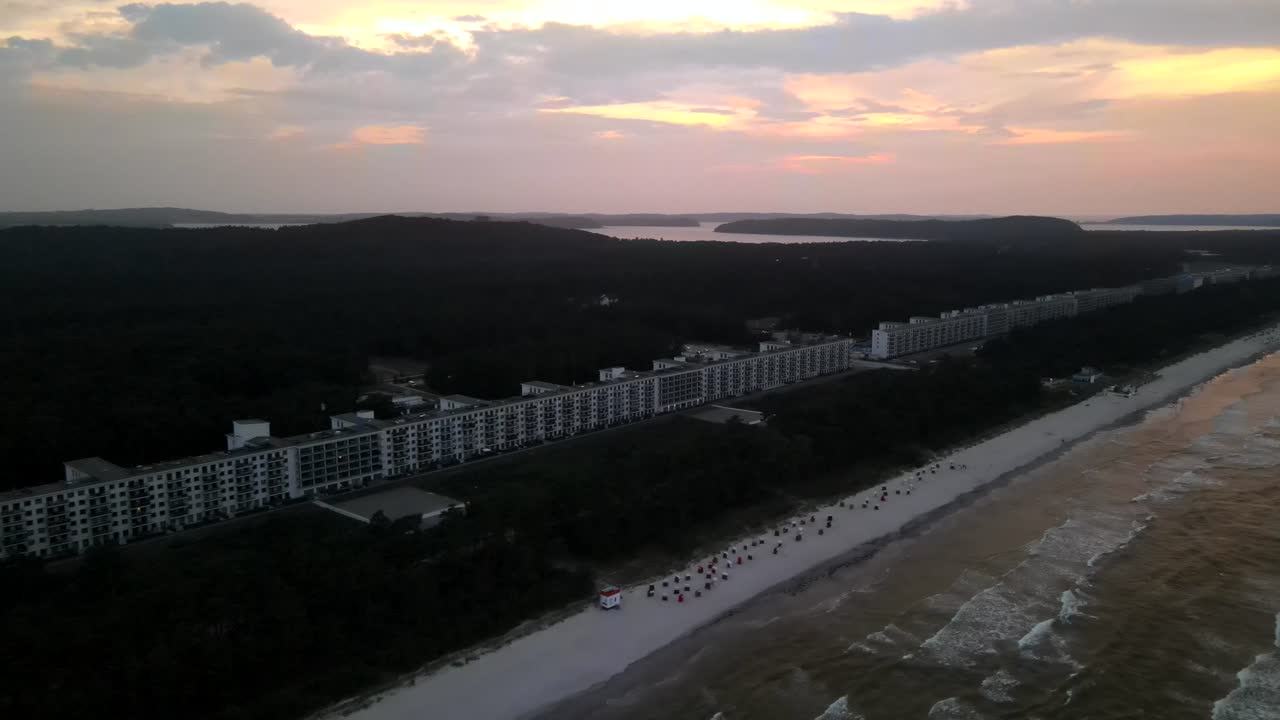 Aerial sunset over Prora, Rügen. The long beachfront complex borders the Baltic Sea, bathed in warm twilight hues.