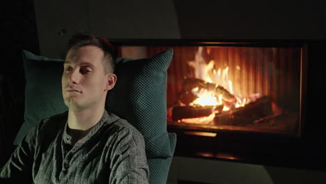 man relaxing by the fireplace at night