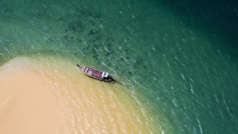 single longtail boat floating at lonely island in thailand, top view, drone
