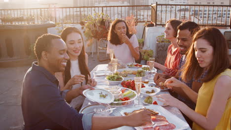 Freunde-Versammelten-Sich-Auf-Der-Dachterrasse-Zum-Essen-Mit-Der-Skyline-Der-Stadt-Im-Hintergrund