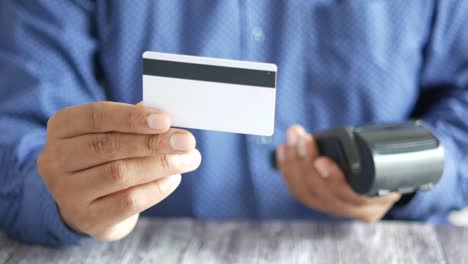 man holding credit card over pos terminal