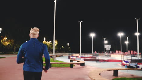 vista trasera de un hombre deportivo corriendo en el parque por la noche