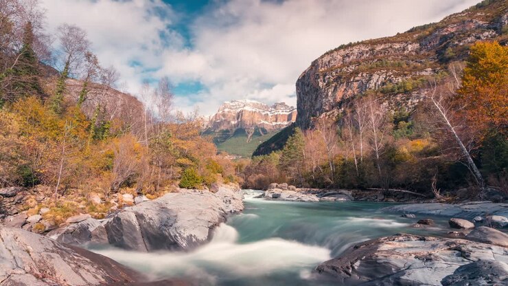 Timelapse del fiume nel Parco Nazionale di Ordesa e del monte Mondarruego, nella stagione autunnale, con un bellissimo cielo blu e nuvole al mattino, sui monti Pirenei