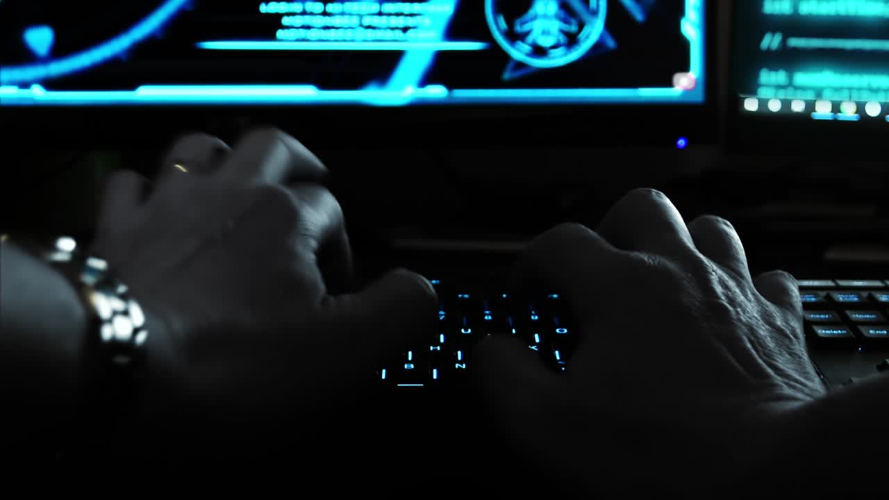 Close up of the hands of a hacker cyber criminal, typing rapidly on a keyboard