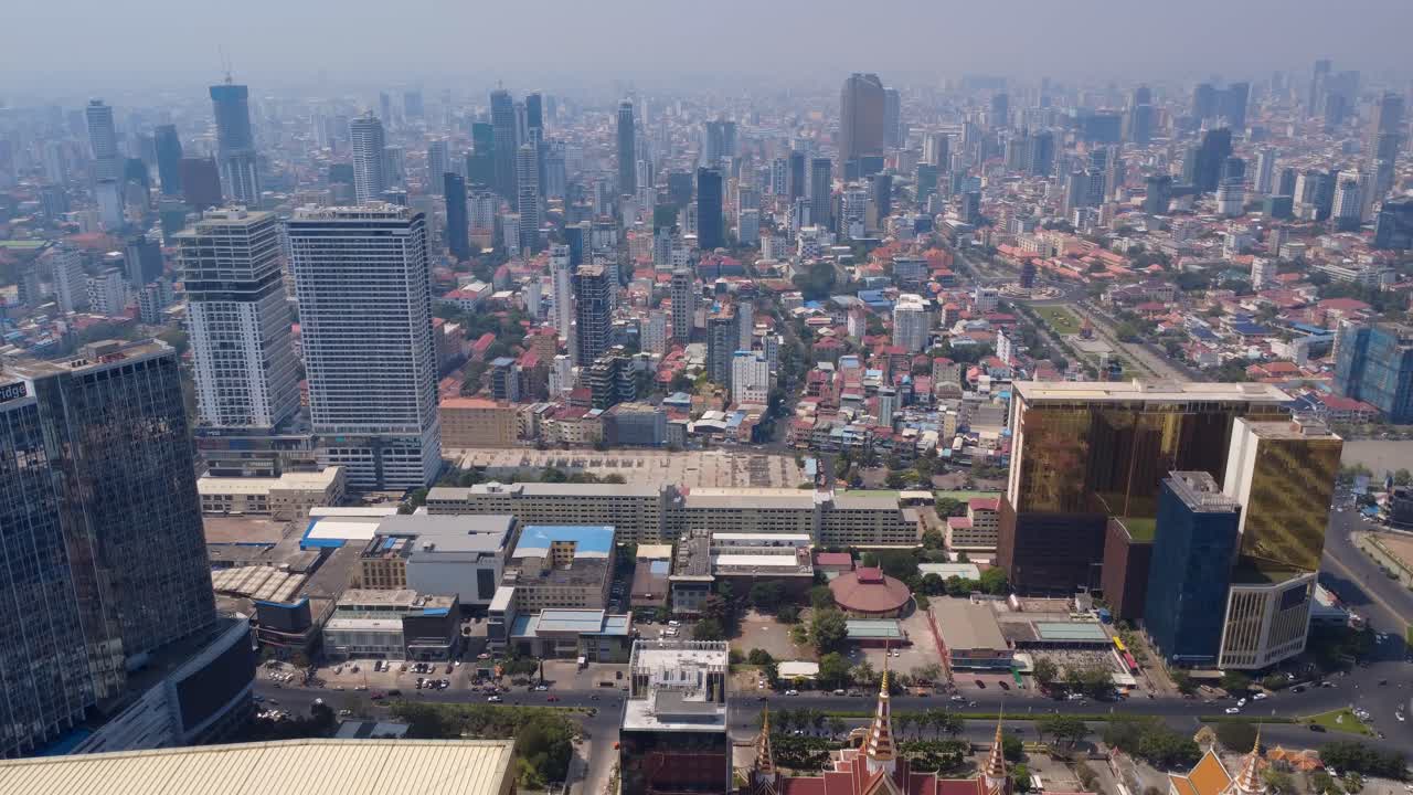 Phnom Penh city under hazy sky due to toxic air pollution with Preah Sihanouk boulevard and historical Independence Monument park on the right, Cambodia skylines, Drone shot