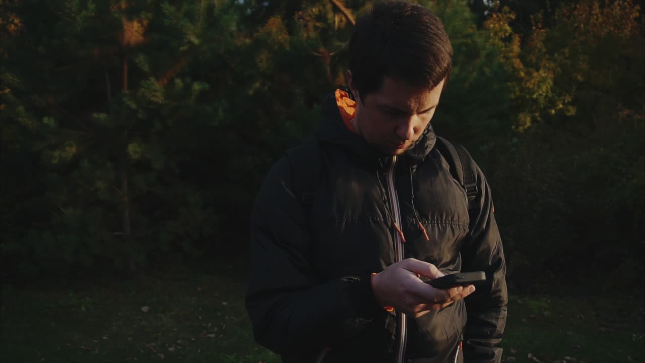 Mand bruger telefon i en park