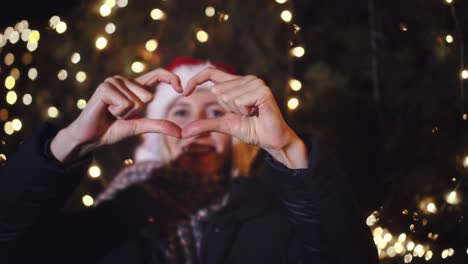 mujer celebra la navidad, sonriendo y mostrando la forma del corazón con sus manos