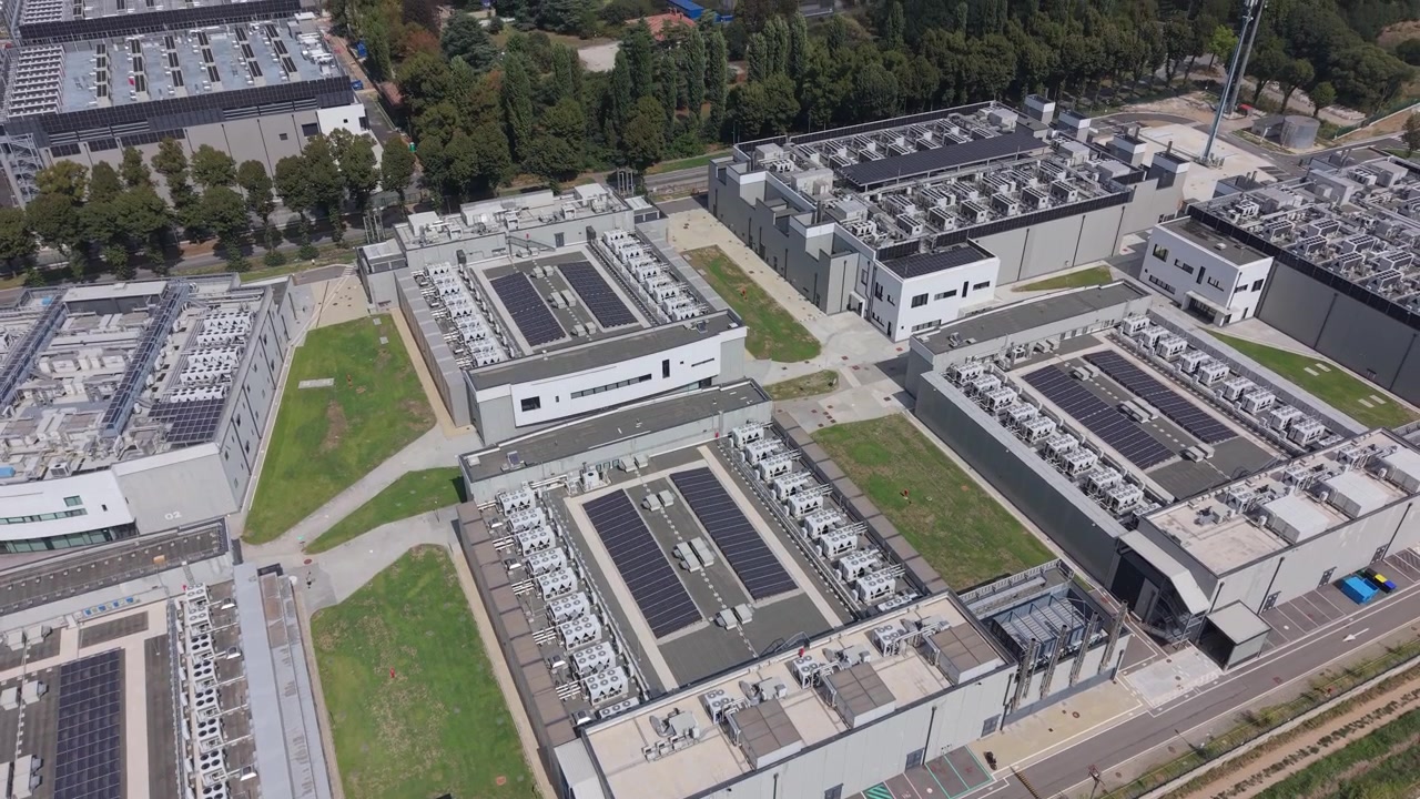Luftfoto af stort datacenterkompleks med flere faciliteter, tekniske systemer, køleudstyr, forsyningsområder og interne veje