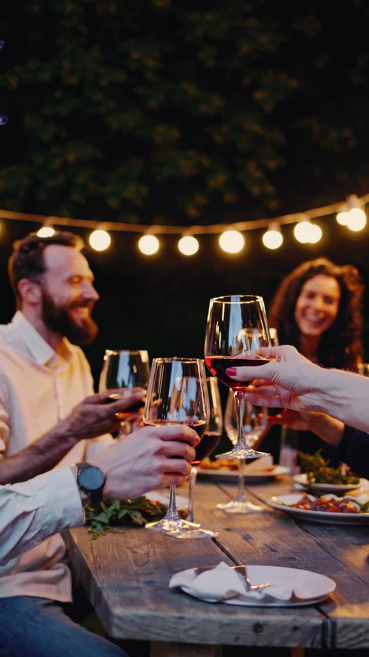 Video still of friends toasting with red wine at an outdoor dinner
