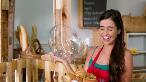 personal femenino sonriente sosteniendo pan recién horneado cubierto con cloche de vidrio