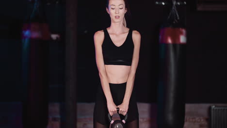 Confident-Young-Woman-Doing-Squats-Exercise-With-Kettlebell-In-Gym