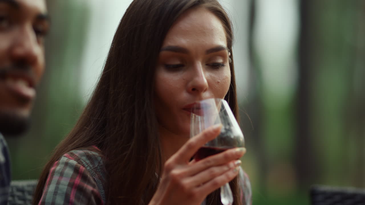 Beautiful girl resting with friends outside. Woman drinking wine on party