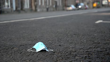 Dirty-medical-face-mask-discarded-on-the-side-of-the-road-in-the-middle-of-the-day