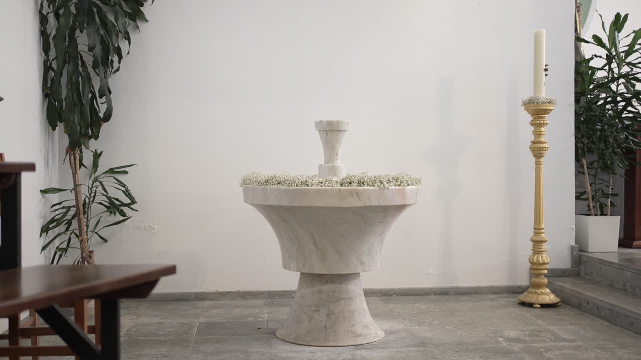 Pila bautismal de mármol decorada junto a una vela en una iglesia tranquila