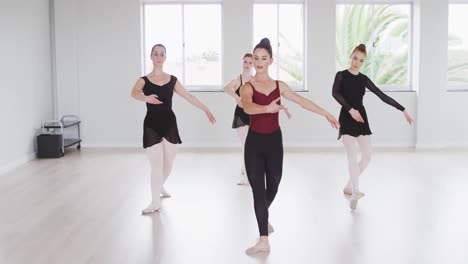 caucasian ballet female dancers exercising with a barre by a mirror during a ballet class