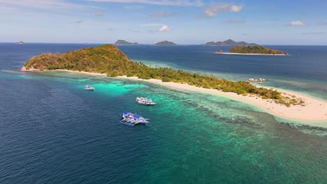 aerial view of manlihan island in linapacan, philippines, featuring turquoise waters, white sand beach, boats, and lush vegetation surrounded by nearby islands under a sunny blue sky
