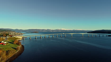 Aerial-drone-forward-moving-shot-over-long-highway-bridge-over-river-with-traffic-driving-by-during-evening-time