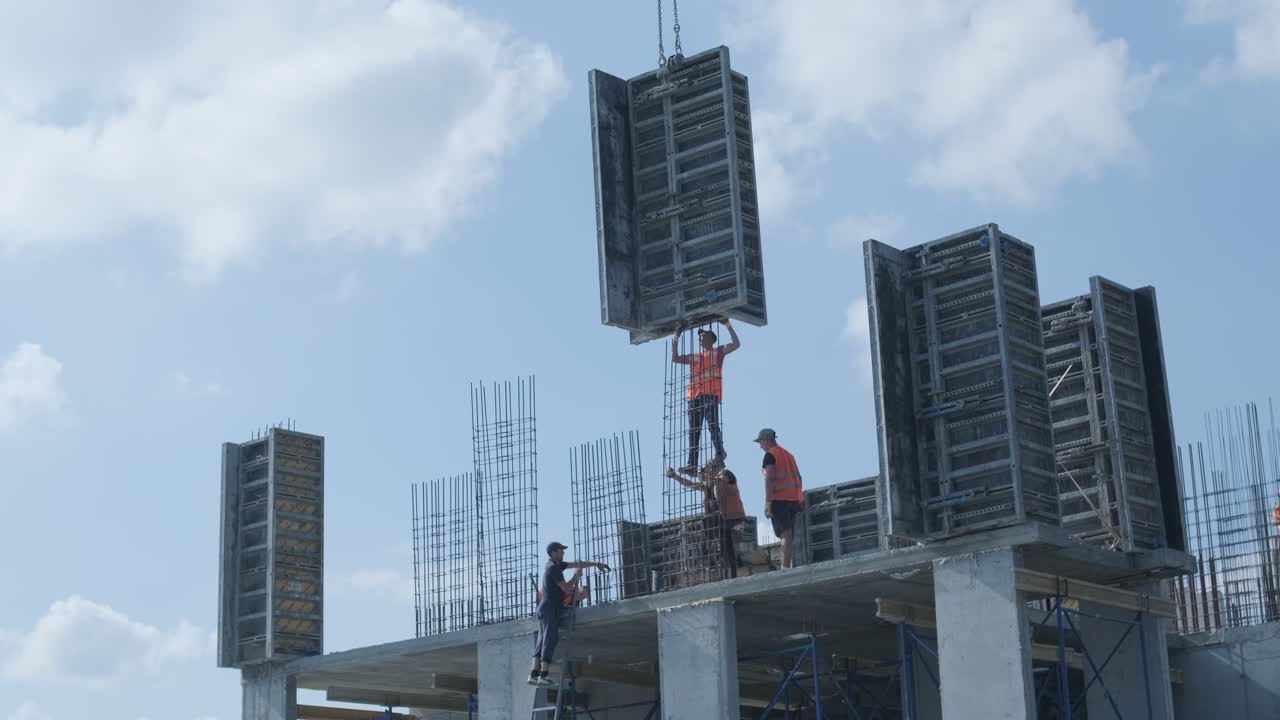 las grúas de torre trabajan en la construcción de edificios residenciales de ladrillo contra el fondo de un cielo azul.