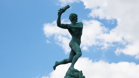 estatua de bronce del monumento brabo contra el cielo azul con nubes en antwerp, bélgica