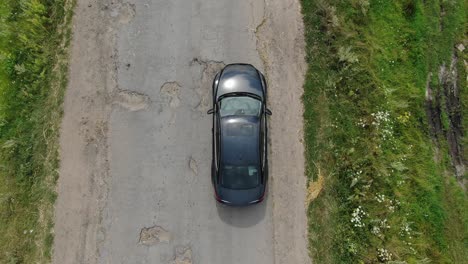 Vista-Aérea-Del-Coche-Evitando-Baches-En-Una-Carretera-Antigua.