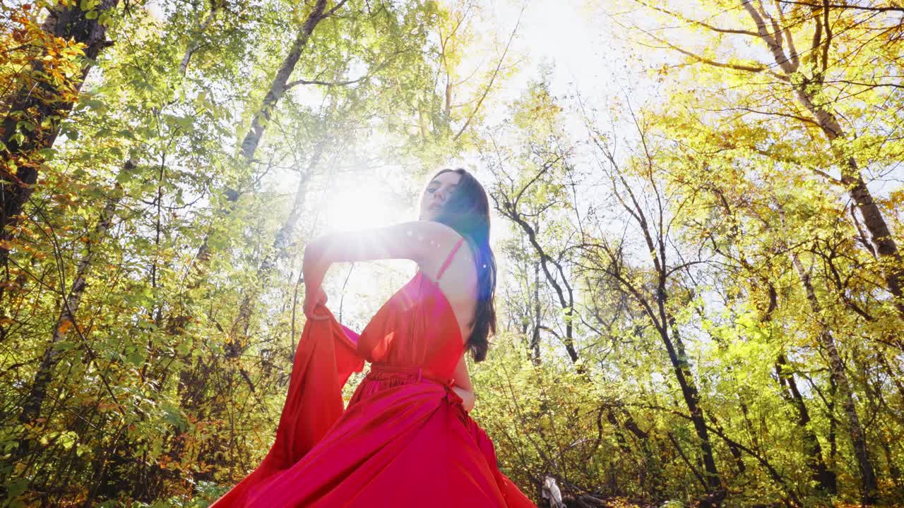 A Glimpse of Grace: A Woman in a Flowing Red Dress Captured in the Golden Glow of Autumn's Embrace within a Serene Forest Setting
