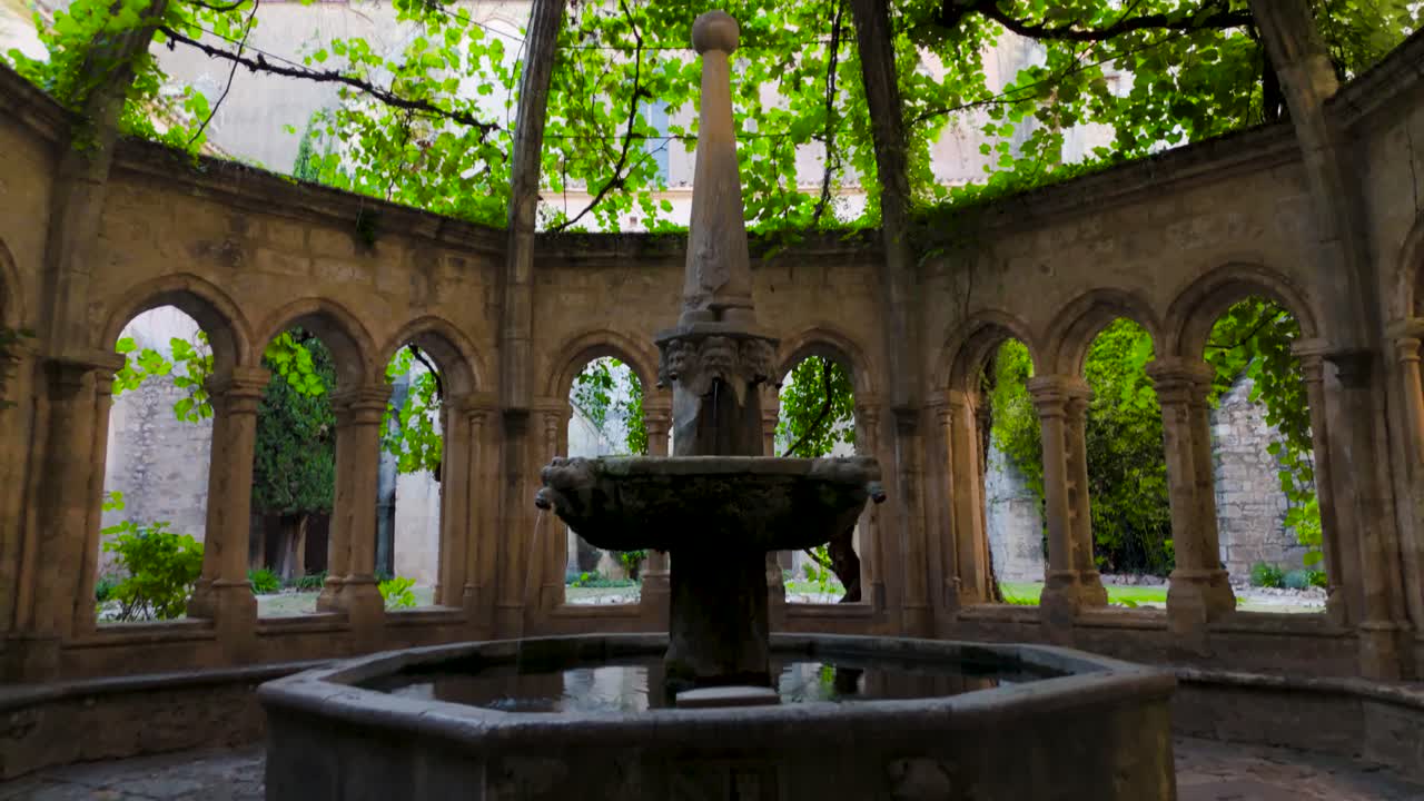 Interior view of half outdoor area in french abbey, beautiful fountain and roof with overgrowing plants.